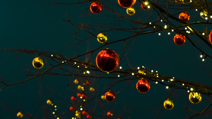 Christmas balls. Large, shiny balls on the branches of a tree. Christmas ornament. Festive garlands on the tree create a festive and magical atmosphere.New year celebration.