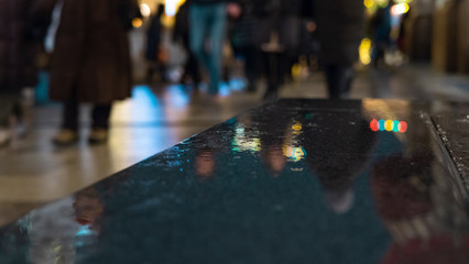 Wet marble slabs. Reflection of lights (Bokeh) on the wet surface of the stone. Cloudy weather with rain in the city.Spilled water on the curb. A template for the design. Abstract background.