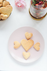 Heart shaped butter cookies on a pink plate and rose on the table. Valentines Day concept