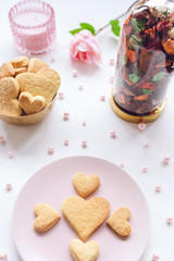 Heart shaped butter cookies on a pink plate, rose and candle on the table. Valentines Day concept