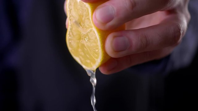 Slow Motion squeeze juice from lemon, hand squeezes half yellow lemon side view.