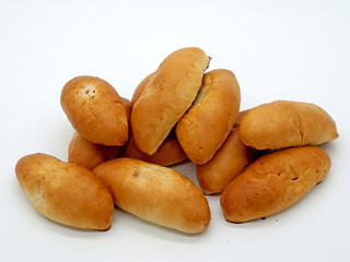 Ready tasty edible baked oval pies, golden color lie on a white background