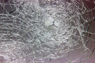 Cracks from shot on window glass on dark background