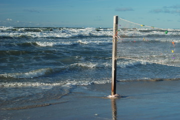 Big waves in the stormy sea, the old volleyball net on the beach