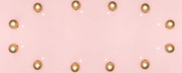 New Year and Christmas composition. Frame from golden balls, white stars on pastel pink background. Top view, flat lay, copy space