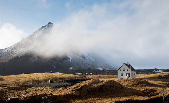 Lonely  house at the small fishing village of Arnarstapi and mountain cliff covered in snow  at Sn&aelig;fellsnes peninsula in Iceland