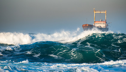 Abandoned ship in the stormy ocean with big wind waves during sunset. © Michalis Palis