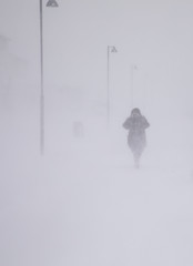 Blizzard in Longyearbyen, woman walking in snowfall. Abstract blurry winter weather background