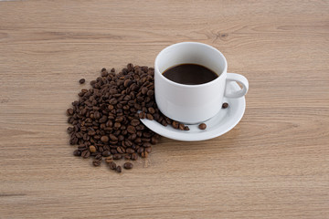 cup of coffee with coffee seeds on wooden table and light brick background