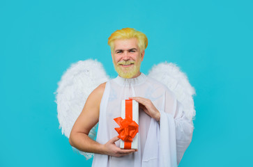 Smiling man in angel costume. February 14. Cupid with gift. Love concept. Cupid with gift box....