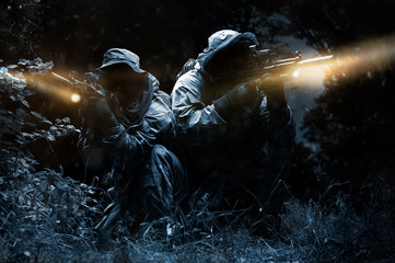 Two fighters of a special unit move through the forest at night. The concept of special operations,...