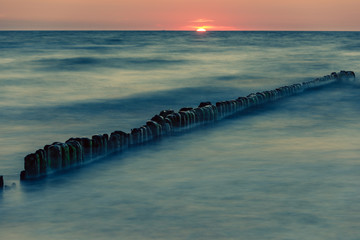 Naklejka premium Wooden breakwater at sunset on the Baltic Sea