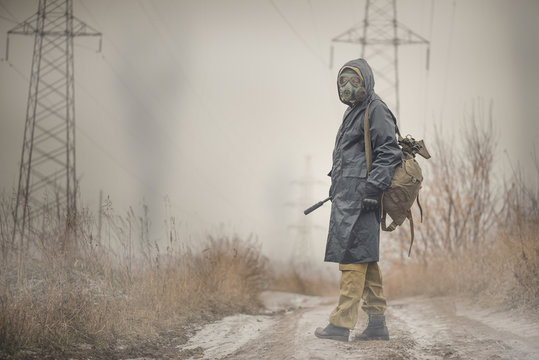 Soldier In Gas Mask And Raincoat With A Rifle Walking On The Empty Road Concept.