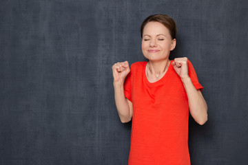 Portrait of happy overjoyed young woman smiling and raising fists up