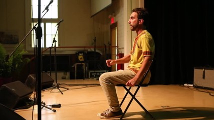 An enthusiastic man is seen on stage telling tales and legends during a spoken word festival dedicated to native American culture and tradition