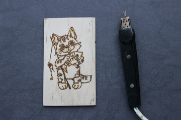 The process of pyrography. Picture with a cat fisherman on a board