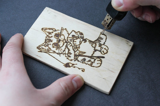 The process of pyrography. Picture with a cat fisherman on a board