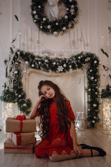 a girl in bright red clothes siting near a fireplace