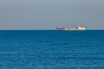 freight ship sailing on the horizon