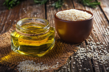 sesame oil and sesame seeds on wooden background