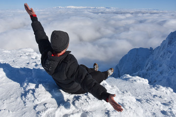 Happy mountaineer raise hand up on top of mountain. Climber enjoy on snowy mountain high above the...