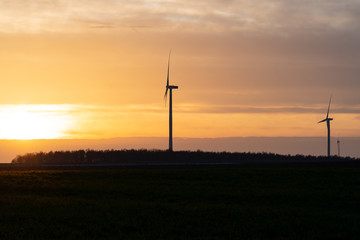Fototapeta na wymiar germany: silhouette of wind turbines, windmills in the sunset, yellow orange sky, with clouds 
