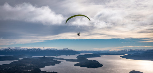 Panoramic view of paragliding over Nahuel Huapi lake and mountains of Bariloche in Argentina, with snowed peaks in the background. Concept of freedom, adventure, flying