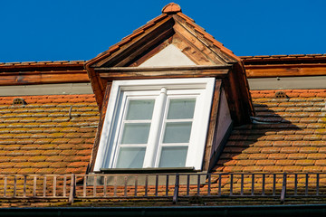 Dormer on a roof with snow grid and blue sky