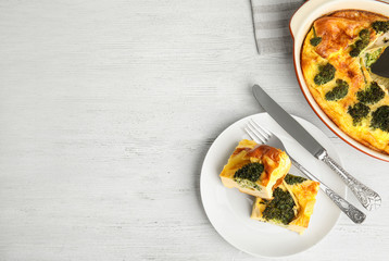 Tasty broccoli casserole served on white wooden table, flat lay. Space for text