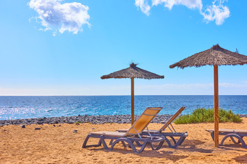 Beach with parasols and chaise longues by the sea