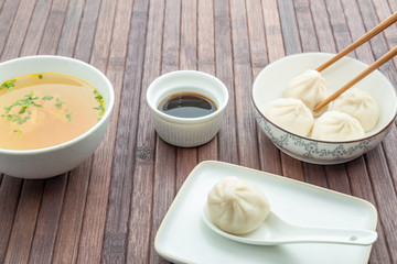 asian table with a preparation of xiaolongbao, soya sauce and a bowl of soup