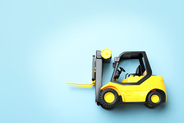 Top view of toy forklift on blue background, space for text. Logistics and wholesale concept
