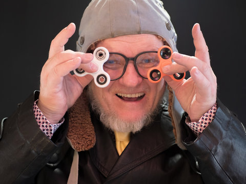 elderly pensioner in pilot's hat, large glasses with gray beard in leather coat. bizarre people. Portrait of strange man who twists a spinner on his nose. Freaky senior citizen. bizarre men