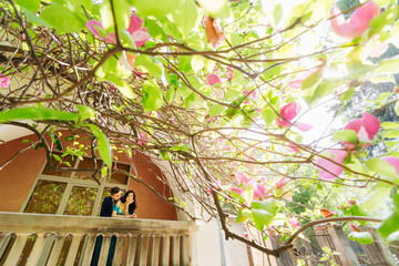 The girl is on the balcony and the guy hugs her from the back si