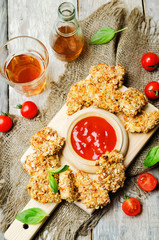 almond crusted chicken tenders with ketchup on a wood background