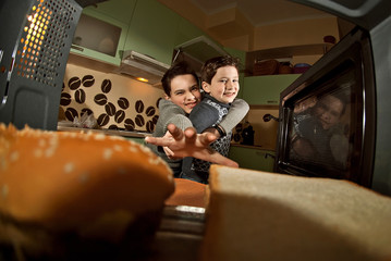 The guys get pizza from the microwave. Food heating in the home kitchen. Fast food. Mid-view view of microwave. Cooking at home. Pizza and burgers are removed from the oven.