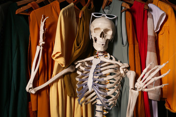 Artificial human skeleton model among clothes in wardrobe