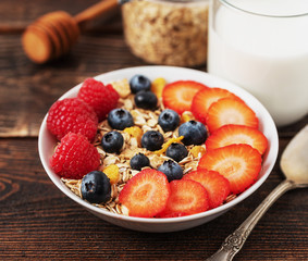Healthy breakfast with oat flakes with blueberries and raspberries on dark desk.