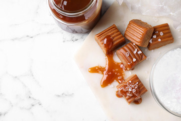 Salted caramel with sauce on marble table, flat lay. Space for text