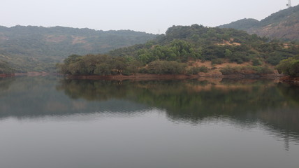 Reflection of a lush green hills over a lake. Scenic background with natural beauty.
