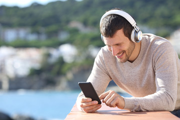 Happy adult man with headphones checking phone content