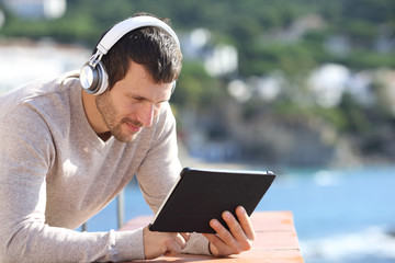 Adult man with headphones checking tablet content
