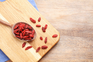 Dried goji berries on wooden table, flat lay. Space for text