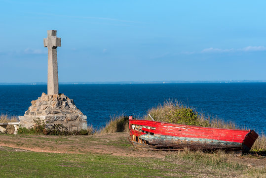 The cross and old broken wooden boat in the hill above the Saint-Gildas-Houat Port in Houat Island.  Brittany, France.
