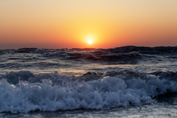 Obraz premium Waves of the Mediterranean Sea with sea foam and spray. Beautiful sea on sunset background. Sundown. Seascape.