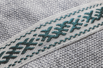 Artistic close-up of traditional symbolic light cyan blue weave combined white threads on white background partial focus