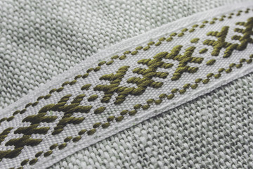 Artistic close-up of traditional symbolic gold weave combined white threads on white background partial focus