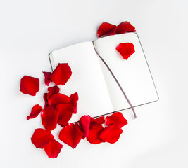Opened notepad and red rose petals