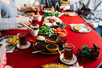 a group of friends are having a breakfast at christmas morning. New Year Breakfast at home. Homemade Breakfast with family with red background. Holding tea and serving breakfast . Traditional Turkish 