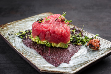 Gourmet fish tartar raw from tuna fillet with hashed avocado, umebashi and Japanese spice as...